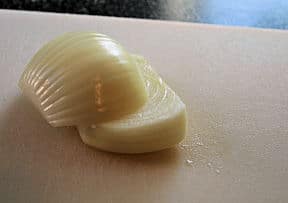 onion sliced in planks on cutting board