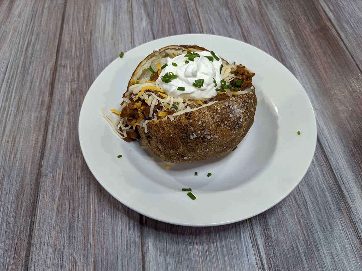 Baked potato topped with chili, cheese, sour cream, and chives