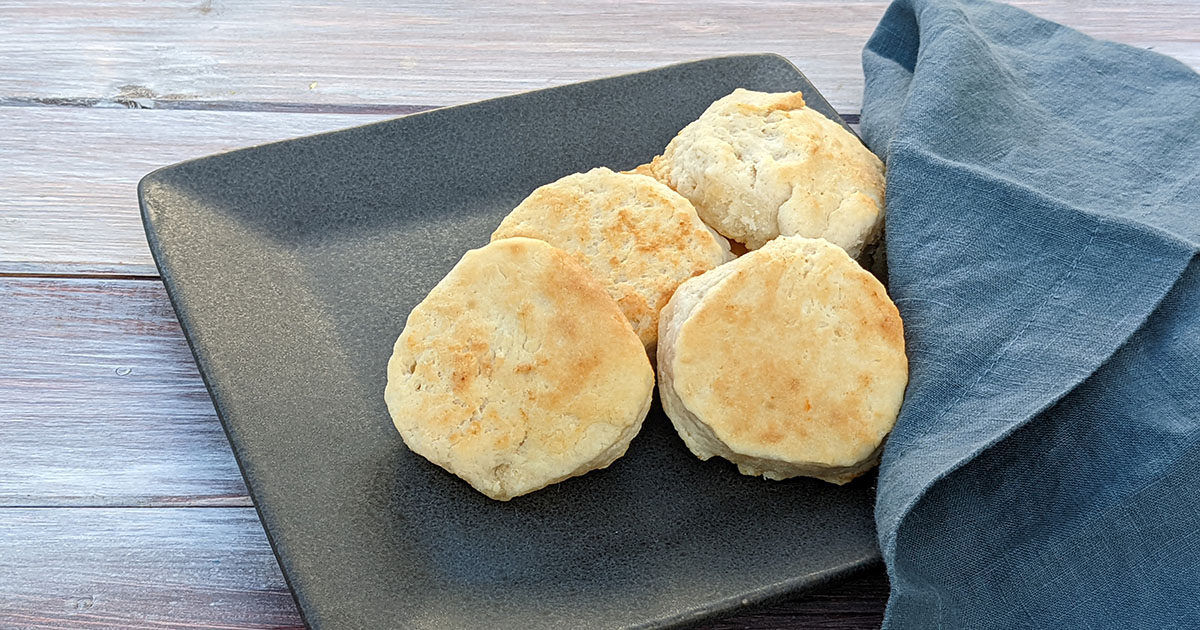 Four biscuits on a dark colored plate with a blue napkin