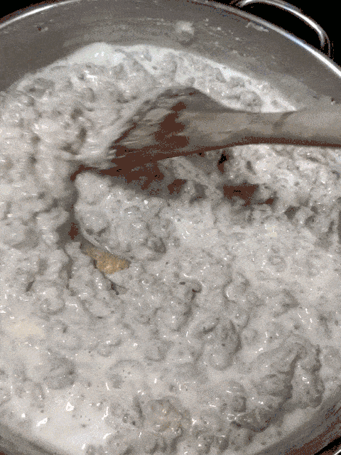 sausage gravy being stirred with a wooden spoon