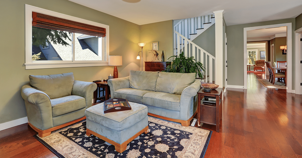 Couch in front of stairs with area rug and ottoman in living room