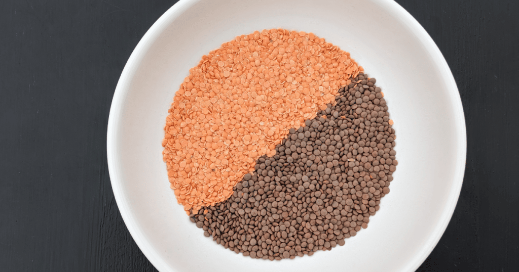 red and crimson dried lentils in a white bowl on a black background